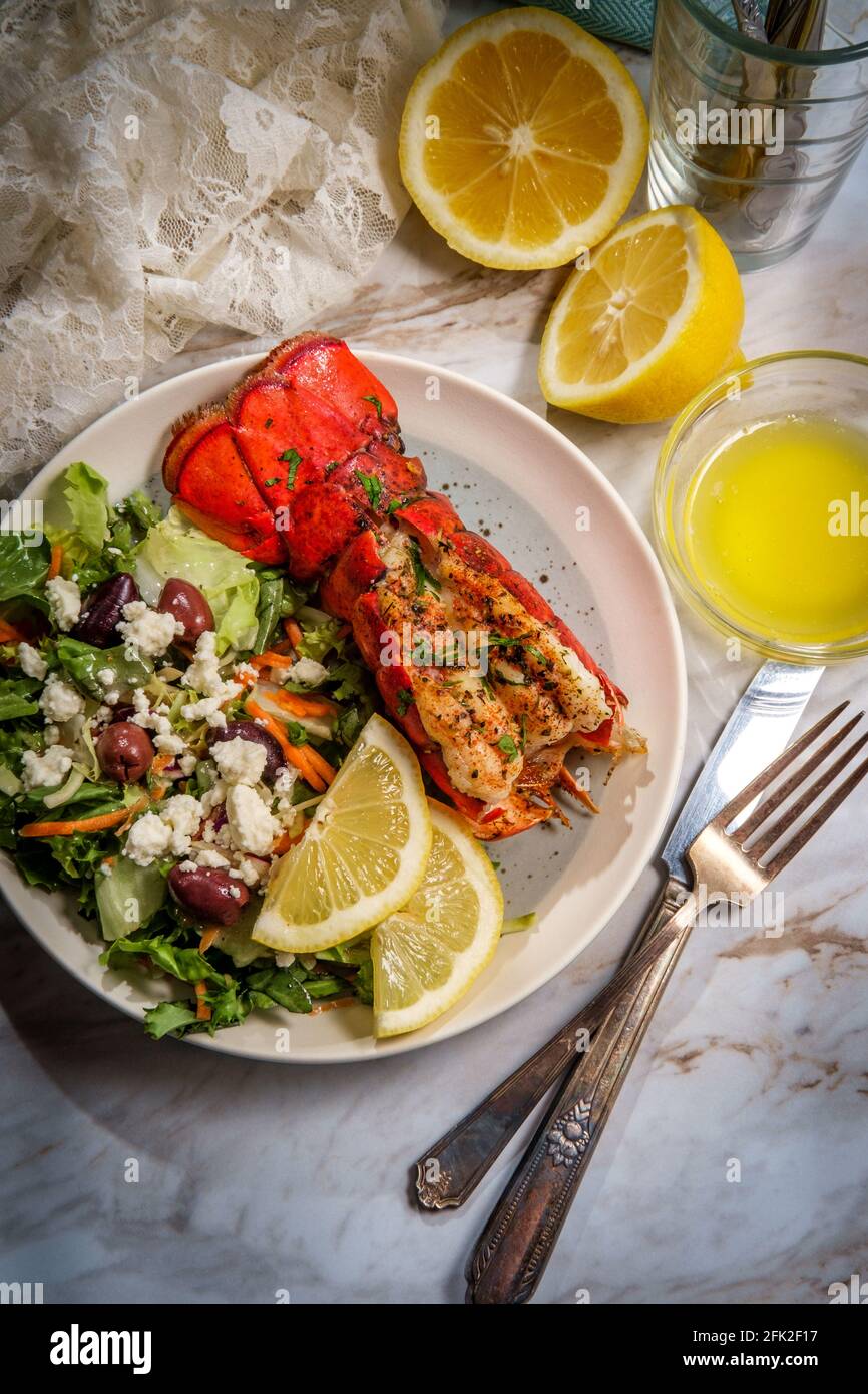 Grilled lobster tail served with fresh Greek salad with sliced lemon