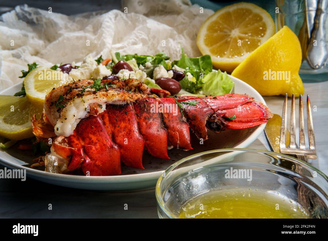 Grilled lobster tail served with fresh Greek salad with sliced lemon