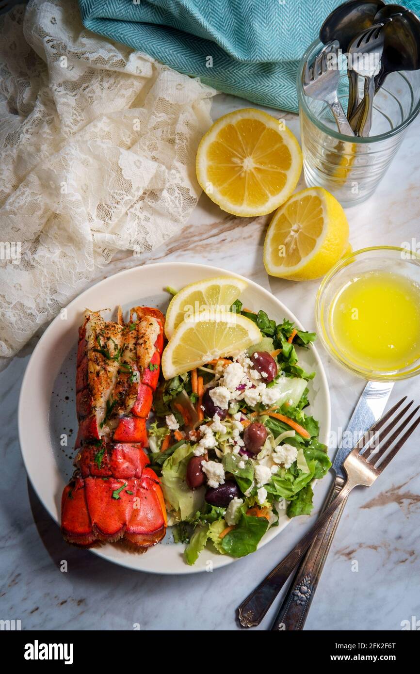 Grilled lobster tail served with fresh Greek salad with sliced lemon