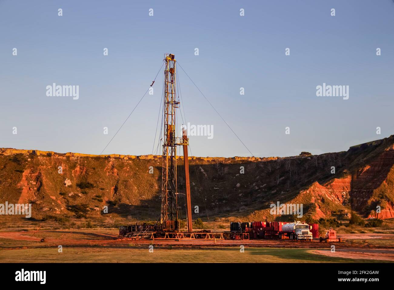 Workover rig working on a previously drilled well trying to restore production through repair in Western Oklahoma with sunset reflecting off red dirt Stock Photo