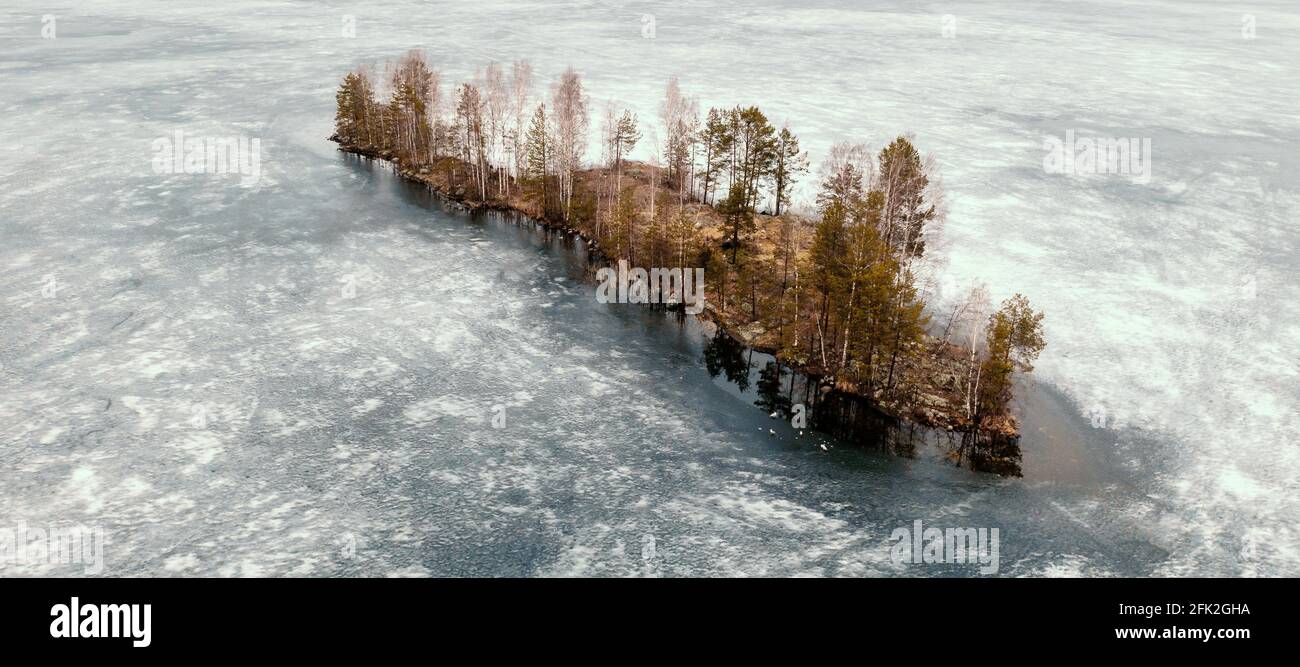 Aerial top view small island in middle of ice-frozen river or lake in Karelia. Stock Photo
