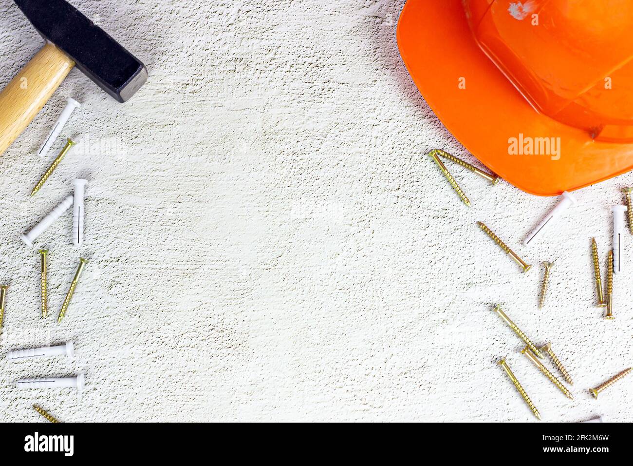 Top view of orange protective hard hat with claw hammer on light gray cement with copy space. Home repairing and improvement, house building concept. Stock Photo