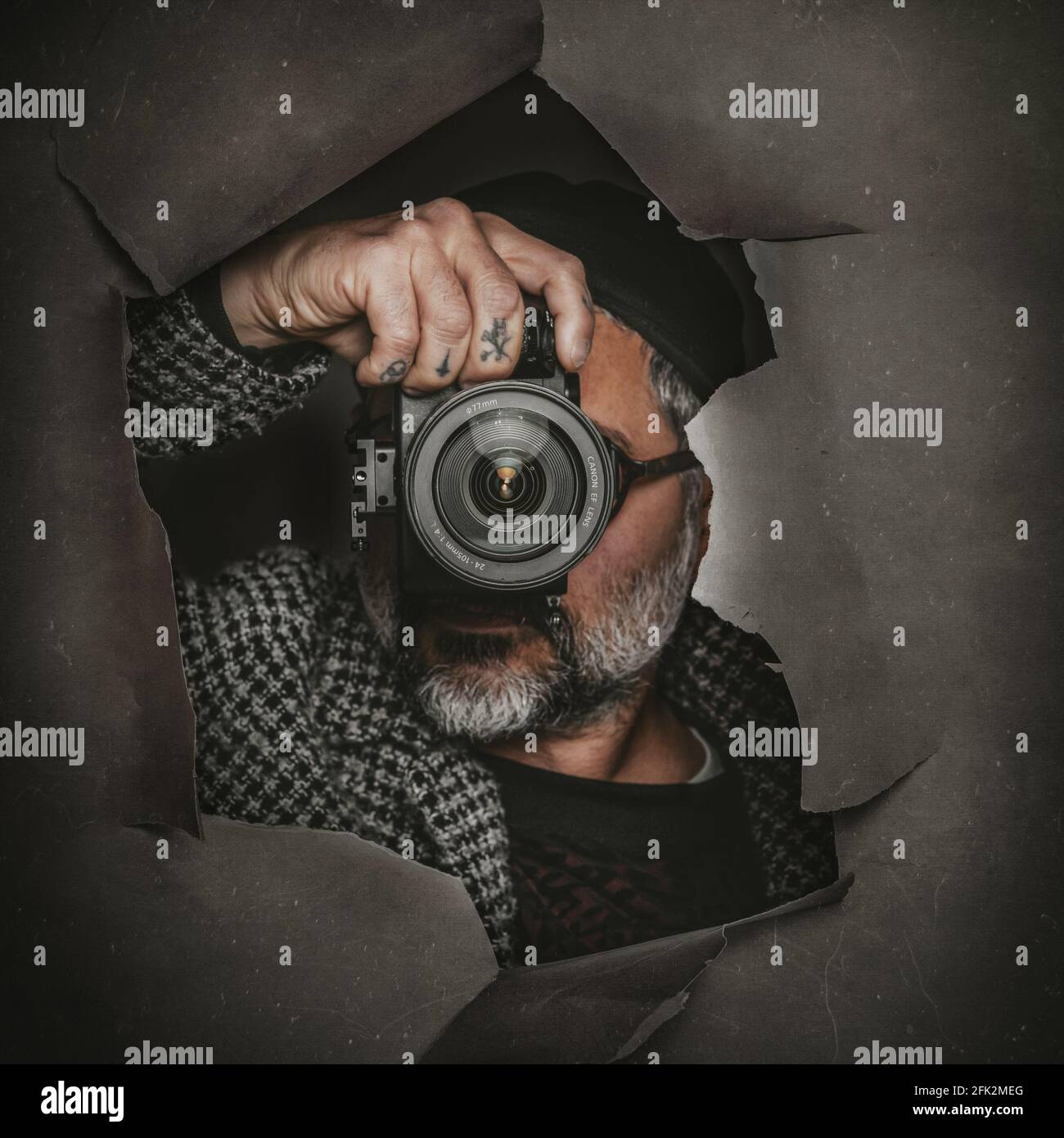 Spanish photographer taking a picture through a ripped paper wall Stock ...