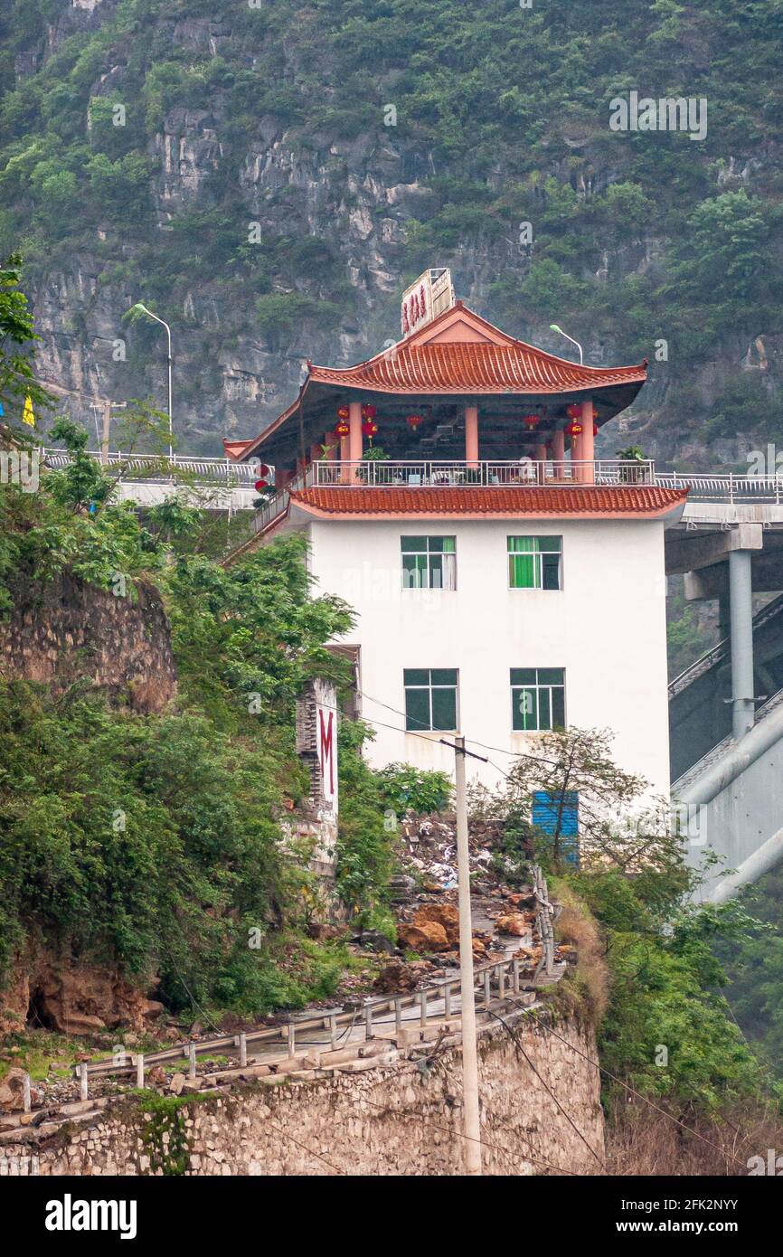 Wushan, Chongqing, China - May 7, 2010: Wu Gorge in Yangtze River. Closeup of white Hotel-Restaurant with red Chinse style roof, built on stilts at en Stock Photo