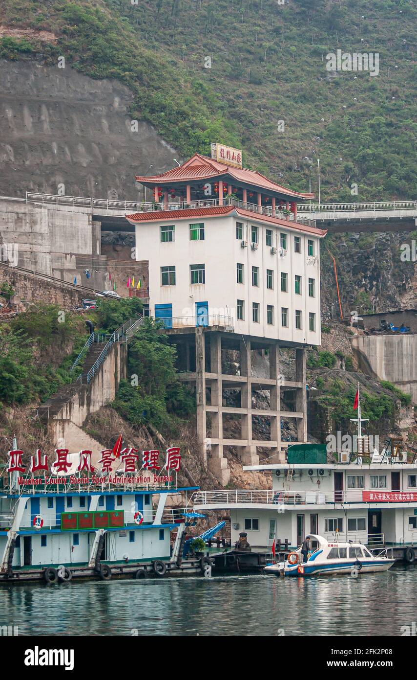 Wushan, Chongqing, China - May 7, 2010: Wu Gorge in Yangtze River. White Hotel-Restaurant with red Chinse style roof, built on stilts above shoreline Stock Photo