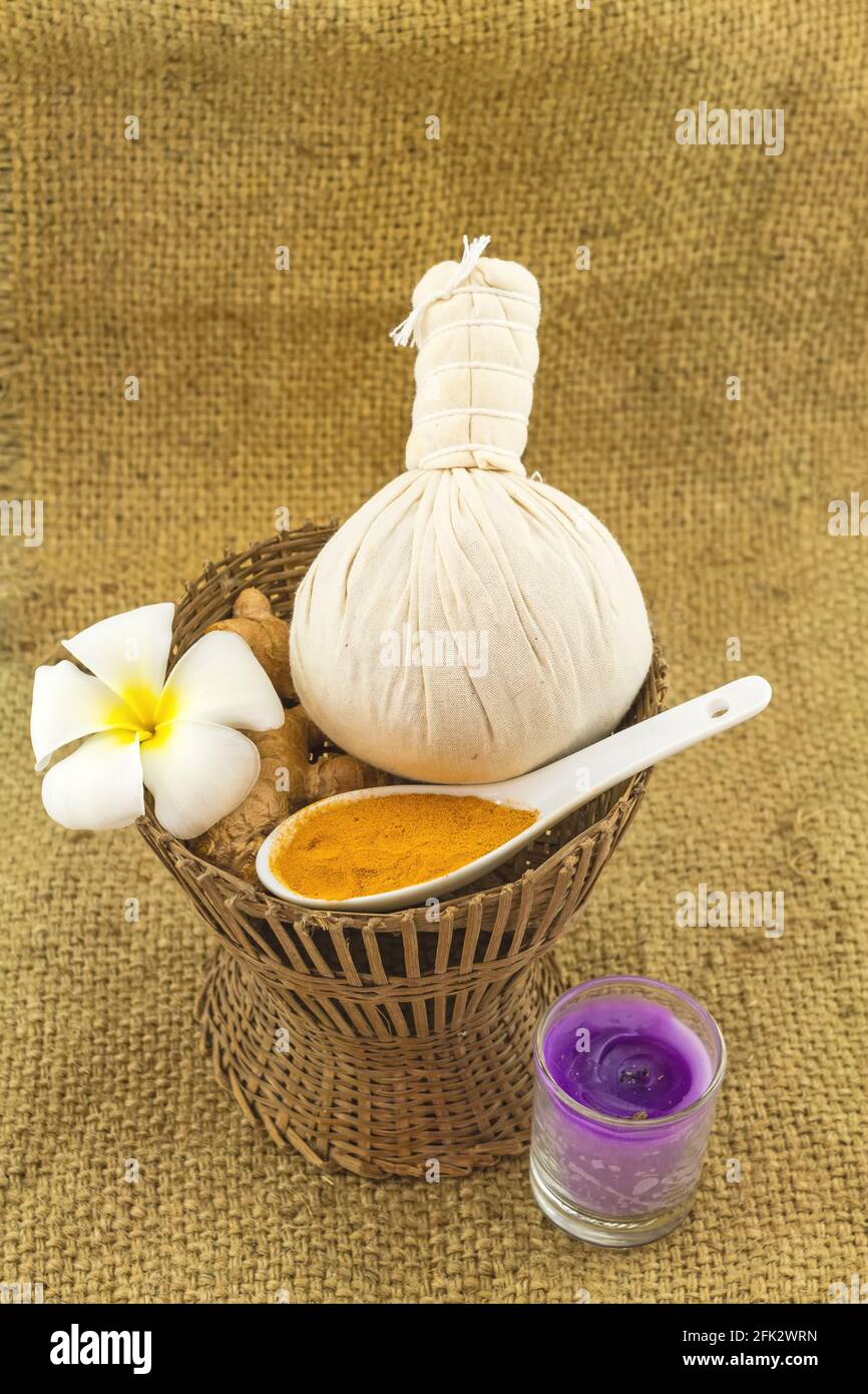 Spa herbal compressing ball , white frangipani flowers (Plumeria spp , Apocynaceae, Pagoda tree, Temple tree) , turmeric powder in white  spoon and ca Stock Photo