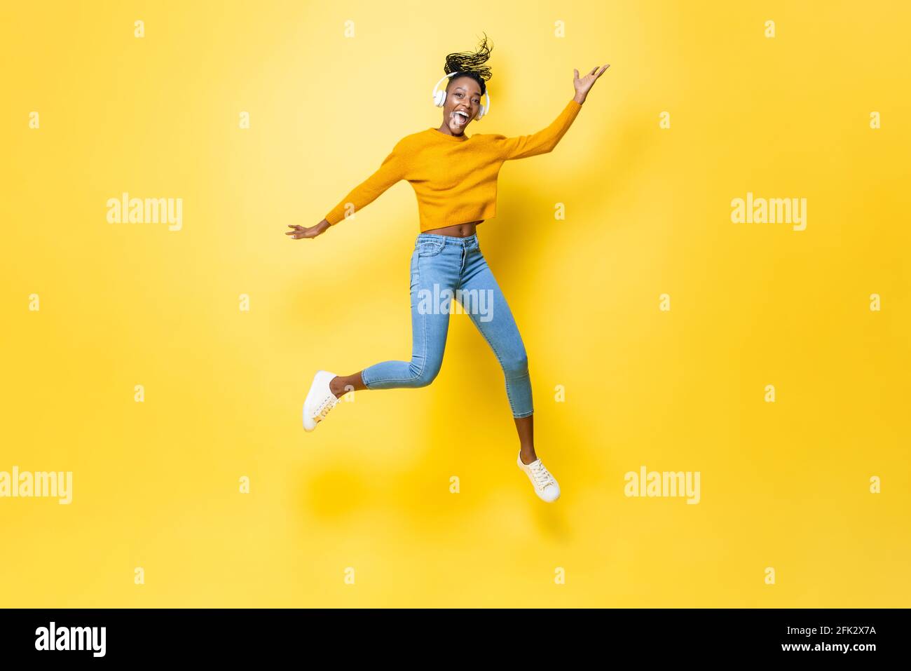 Happy energetic young African American woman wearing headphones ...