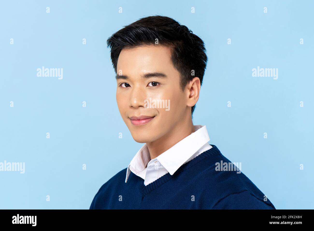 Close up portrait of young handsome Asian man face on light blue studio background Stock Photo
