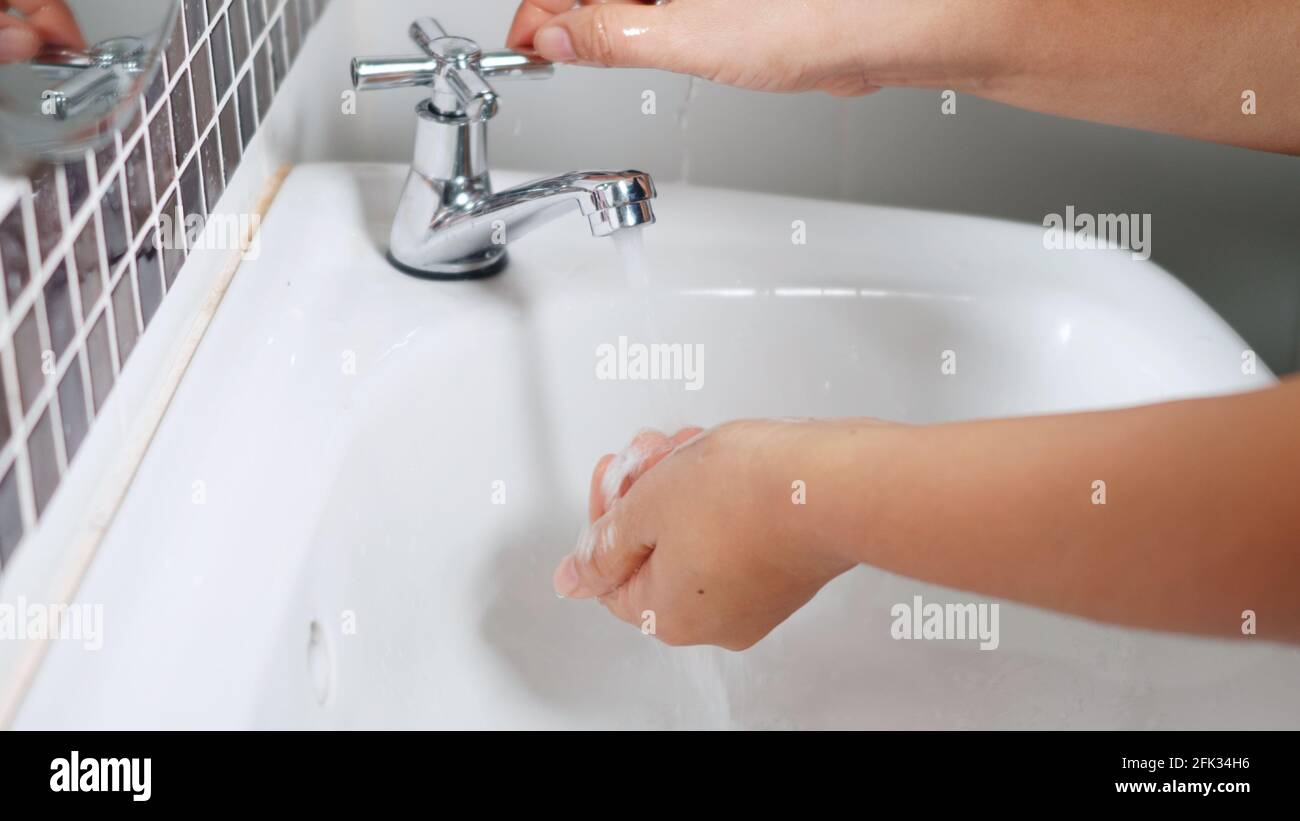 Closeup young woman hands using soap and washing hands under the water ...