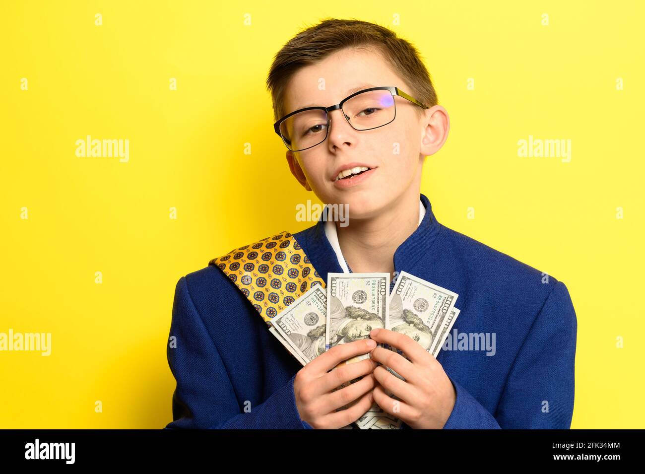 A boy in glasses and an oversized suit with a satisfied face is holding