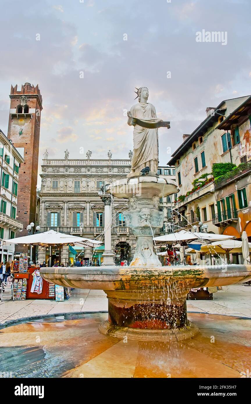 The ancient Roman sculpture of Madonna Verona Fountain, located in Piazza Erbe square, the brick Gardello Tower and Palazzo Maffei (Palace) are seen i Stock Photo