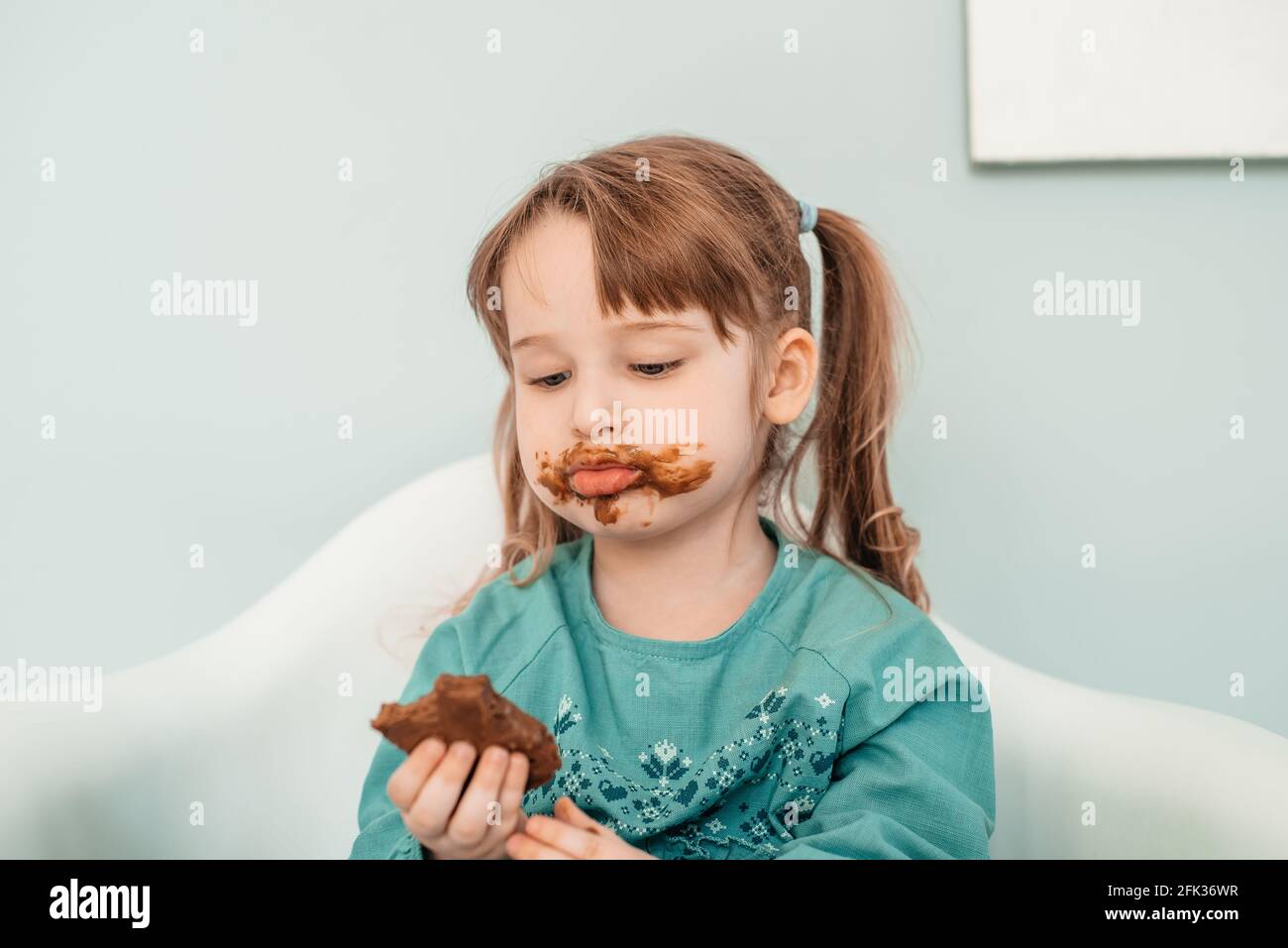Adorable baby girl with face covered in chocolate. Stock Photo