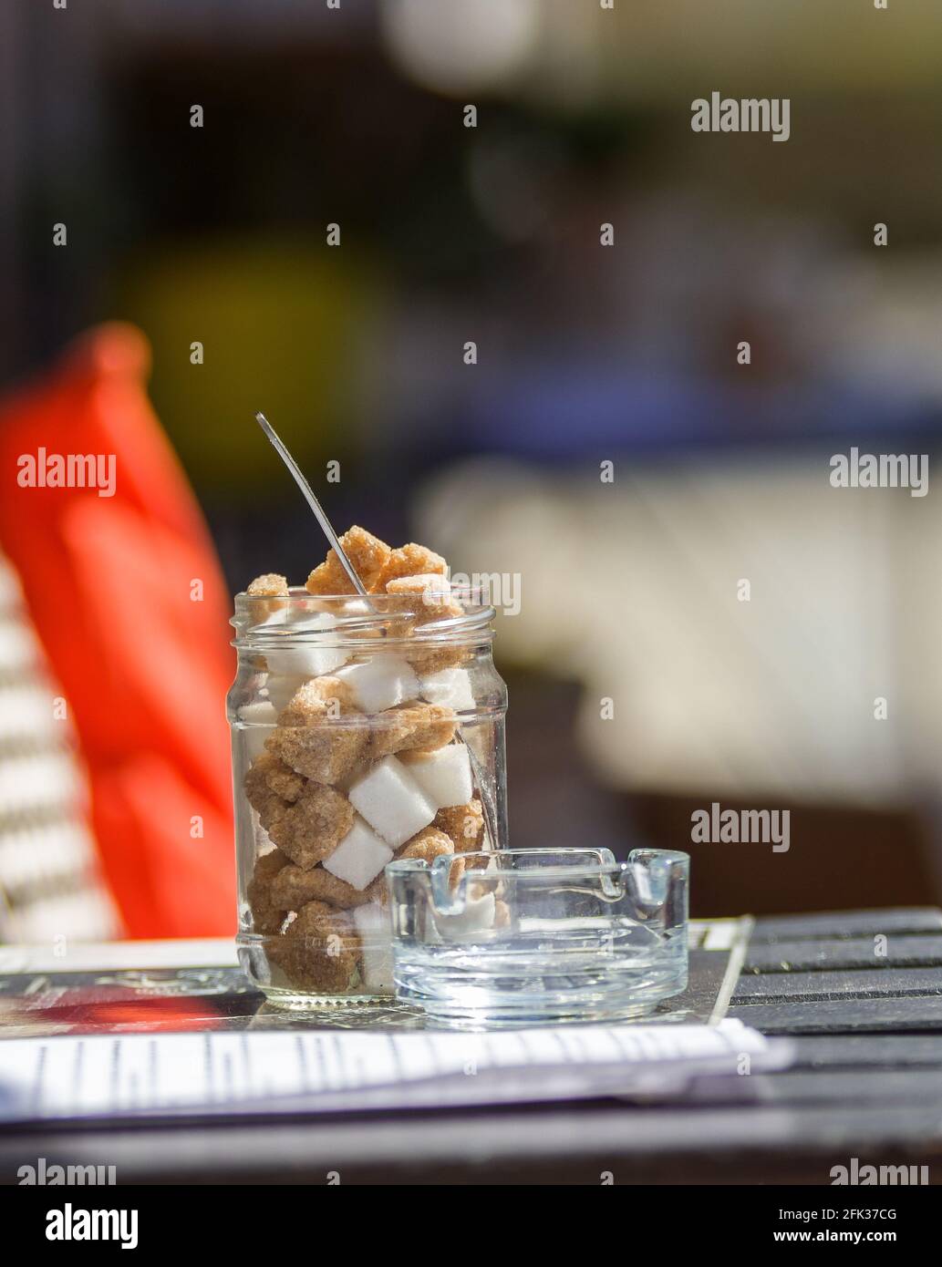 Jar of sugar and ashtray on a small coffee table, basic equipment of a street cafe Stock Photo