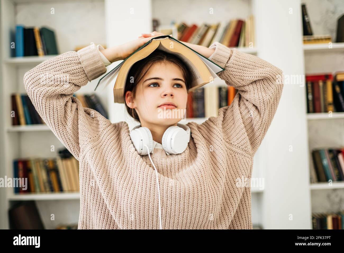 Young girl standing near the bookshelf in library Stock Photo - Alamy