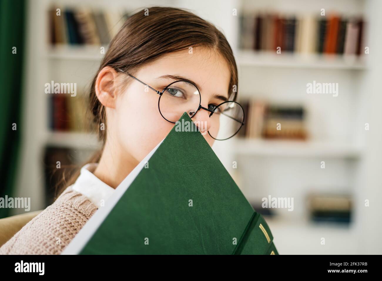 Young girl standing near the bookshelf in library Stock Photo - Alamy