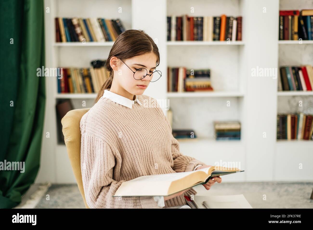 Young girl standing near the bookshelf in library Stock Photo - Alamy
