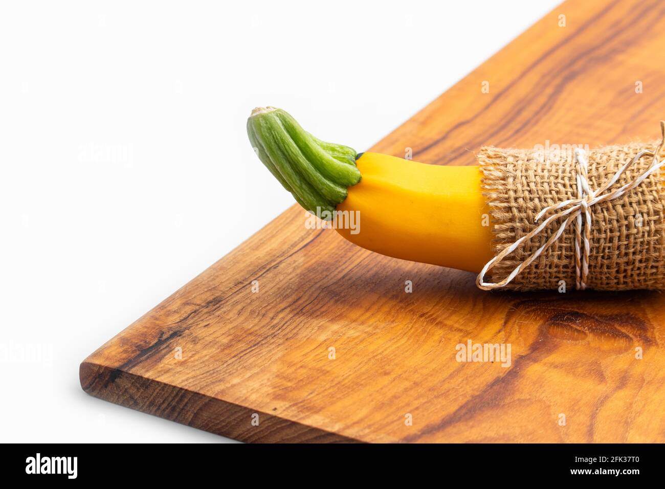 Single Summer Squash Zucchini, Yellow Colored Gourd Also Known As Courgette, Baby Marrow, Indian Jugni Sabzi Or Jugnu Petha Sabji Tied In Burlap Cloth Stock Photo