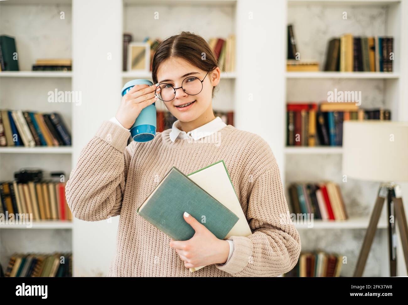 Young girl standing near the bookshelf in library Stock Photo - Alamy