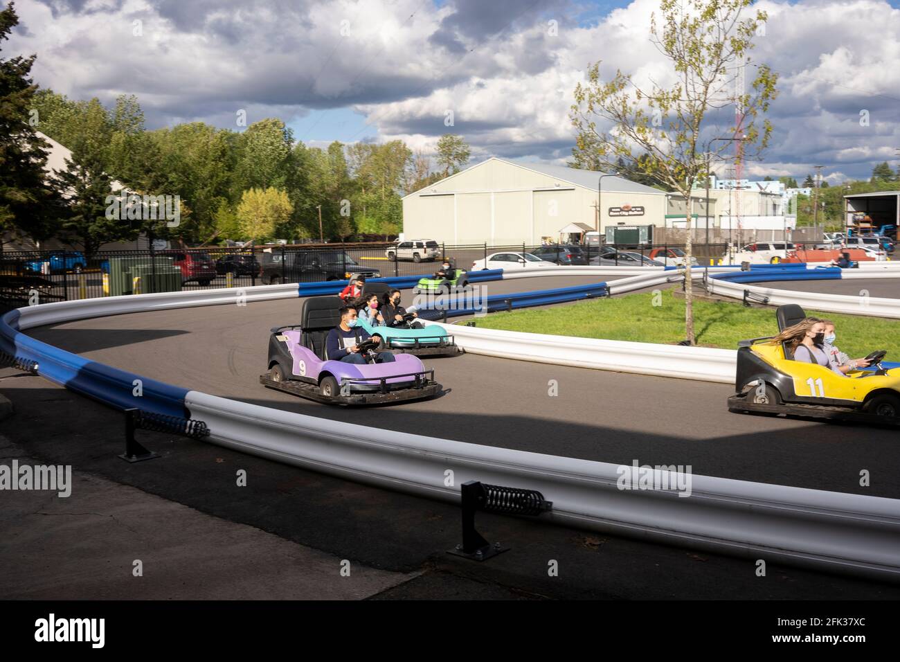 Masked visitors kart racing in Portland's Oaks Amusement Park that reopens in compliance with COVID mandates on Sunday, April 25, 2021, amid the pandemic. Stock Photo