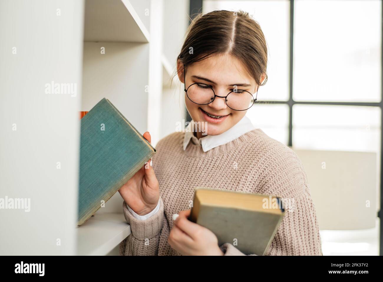 Young girl standing near the bookshelf in library Stock Photo - Alamy