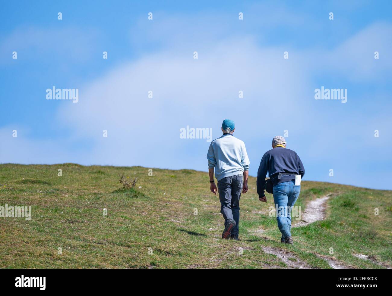 Pair of man walking / hiking up a hill on Monarch's Way (see more info) in the British countryside in Arundel Park in West Sussex, England, UK. Stock Photo