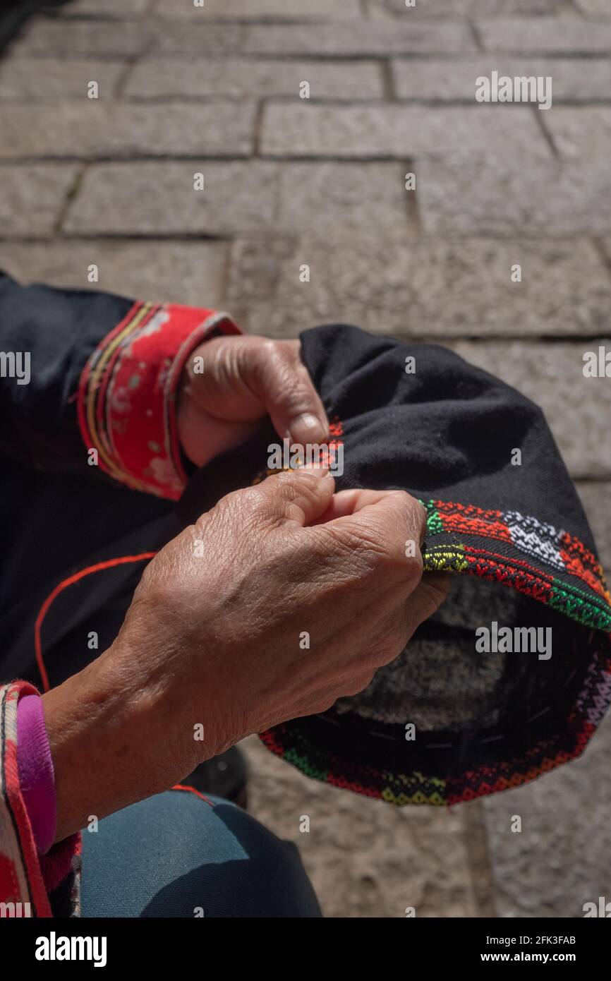 an old woman embroidering under the sun in the costume of yao nationality China Stock Photo