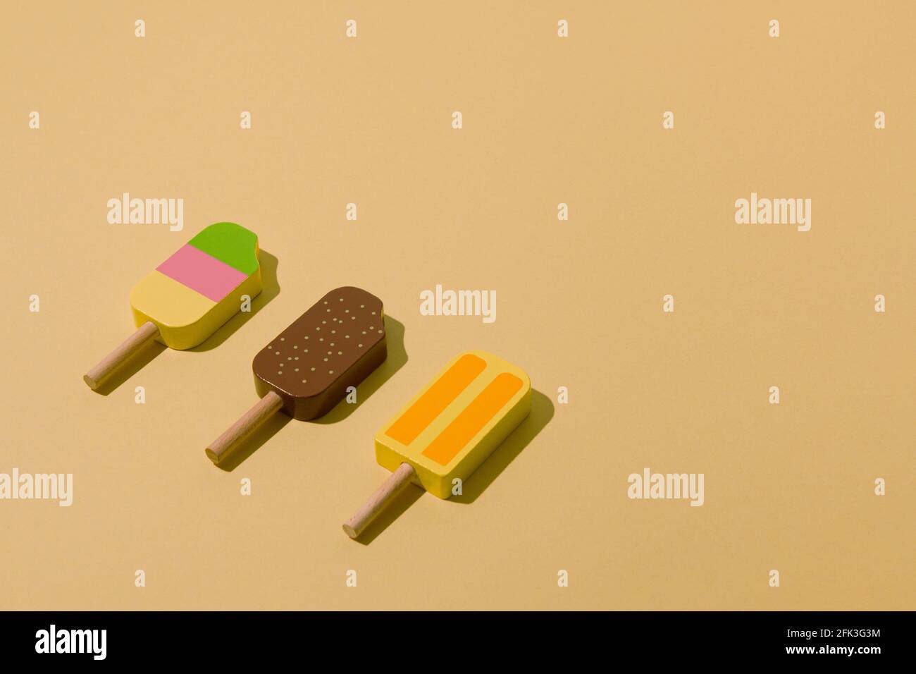 Colorful sunlit popsicles on a pale yellow background. Minimal ice cream layout. Stock Photo