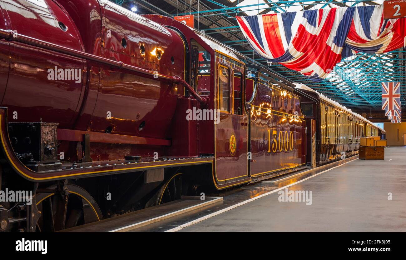 York, North Yorkshire, England. 1926 LMS steam locomotive and royal carriages on display beneath Union Jacks at the National Railway Museum. Stock Photo
