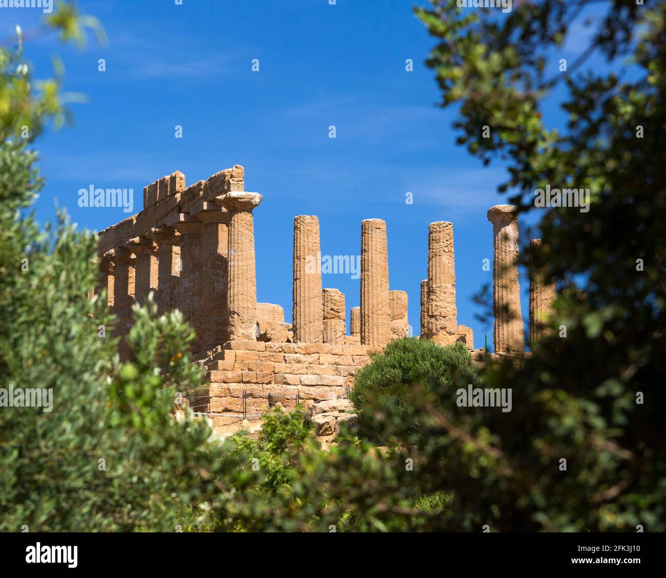 Agrigento, Sicily, Italy. View through green foliage to the Temple of Hera, Valley of the Temples. Stock Photo