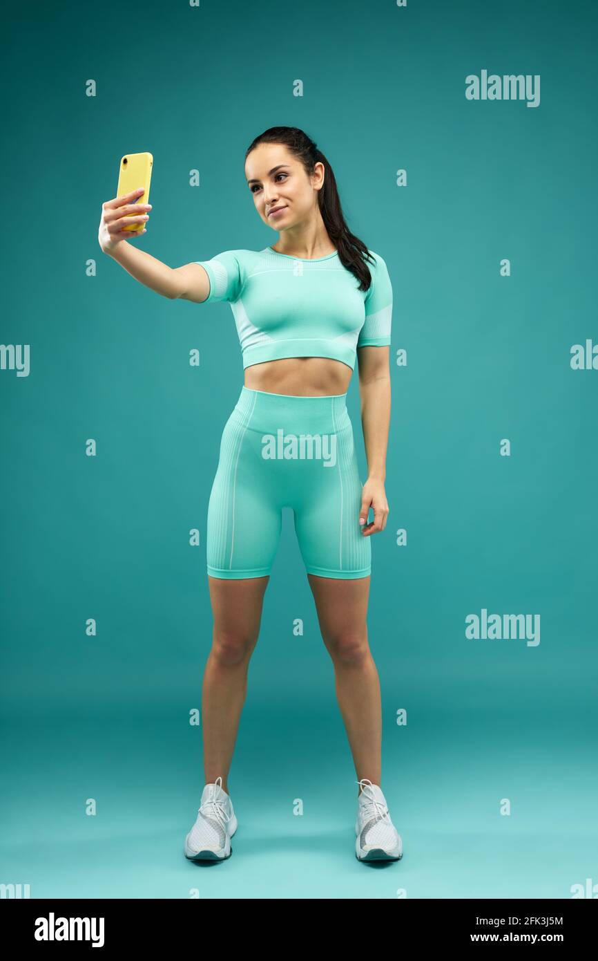 Cheerful young woman in sportswear making selfie Stock Photo