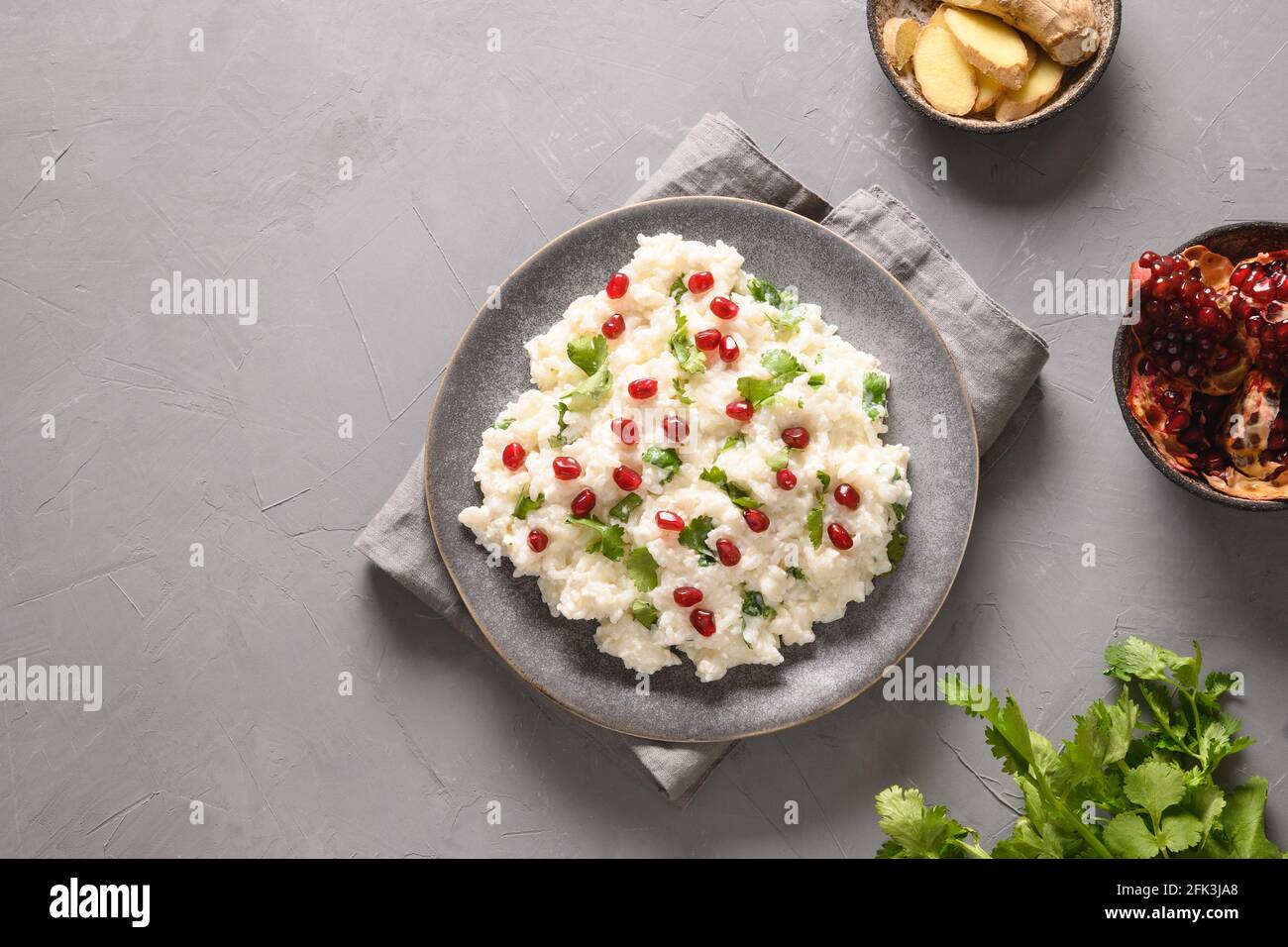 Curd Rice with cashews, grapes, cilantro on a grey background. Top view. Traditional Indian South cuisine Stock Photo