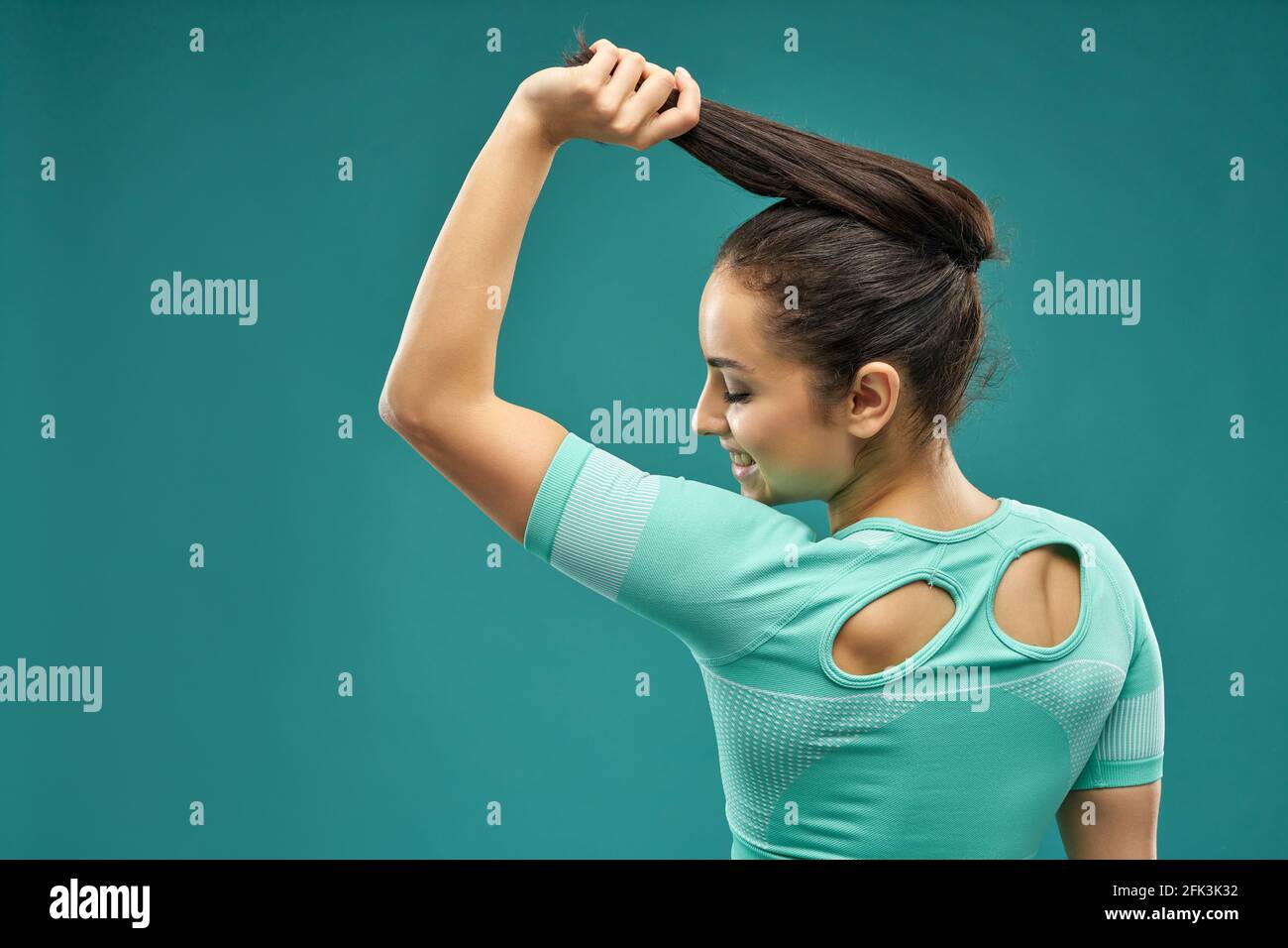 Cheerful young woman in sportswear holding her ponytail Stock Photo