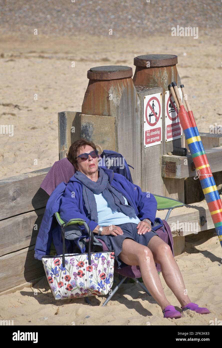 lone older woman fast asleep in afternoon sun southwold beach suffolk england Stock Photo