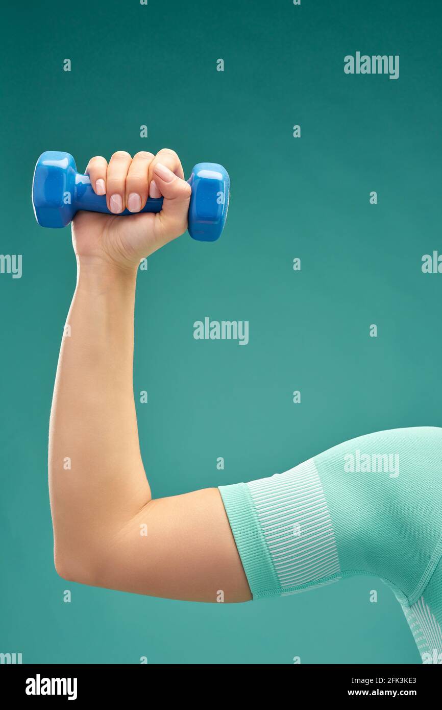 Sporty young woman with dumbbell demonstrating her biceps Stock Photo