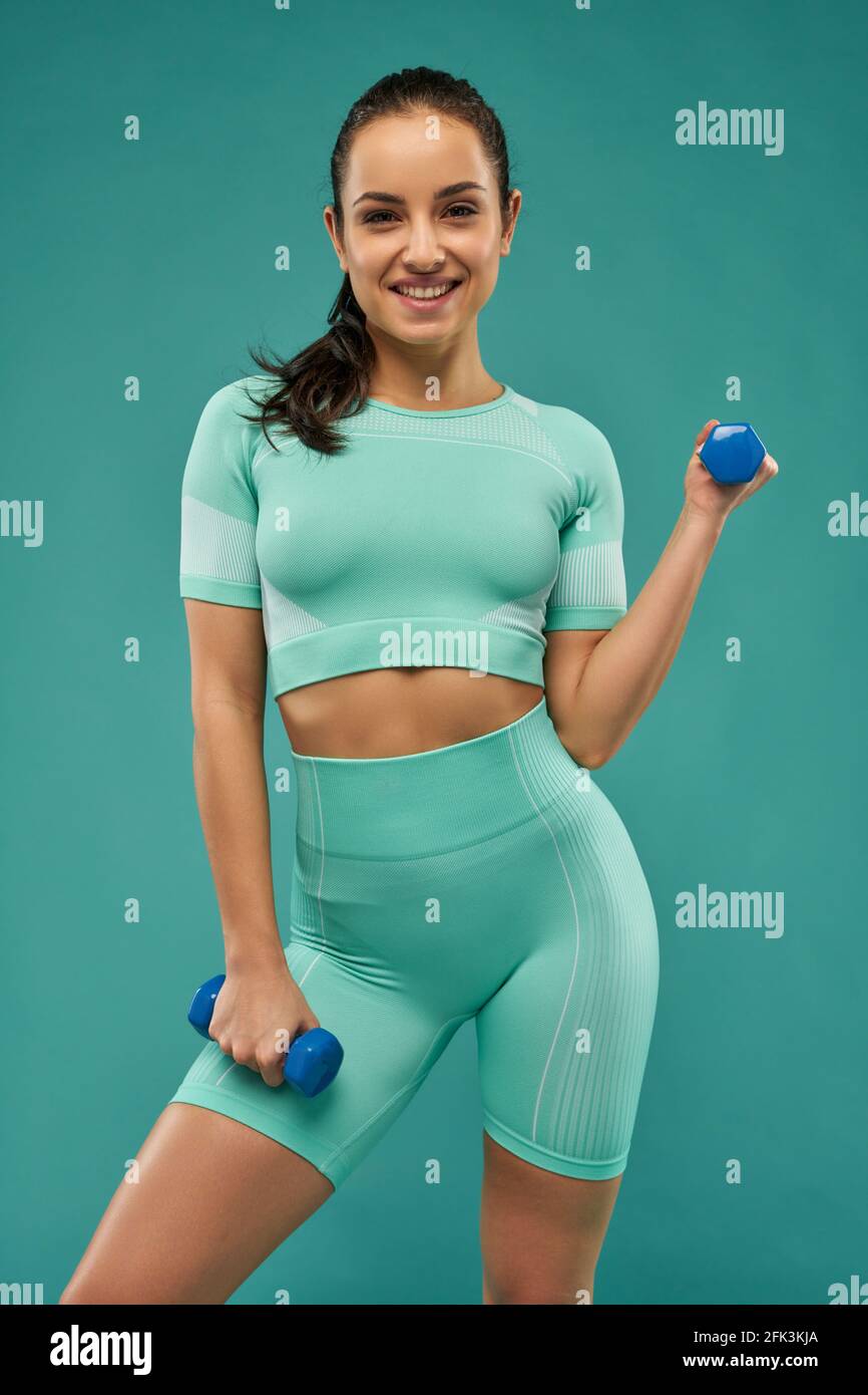 Joyful young woman doing exercise with dumbbells Stock Photo