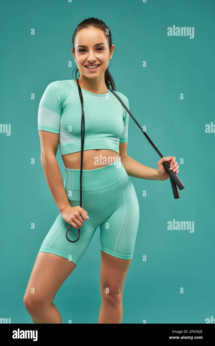 Cheerful young woman with skipping rope posing in studio Stock Photo