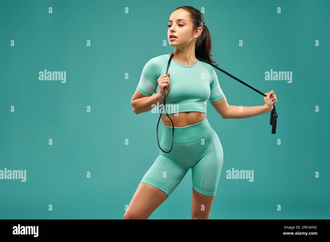 Sporty young woman with jump rope posing in studio Stock Photo
