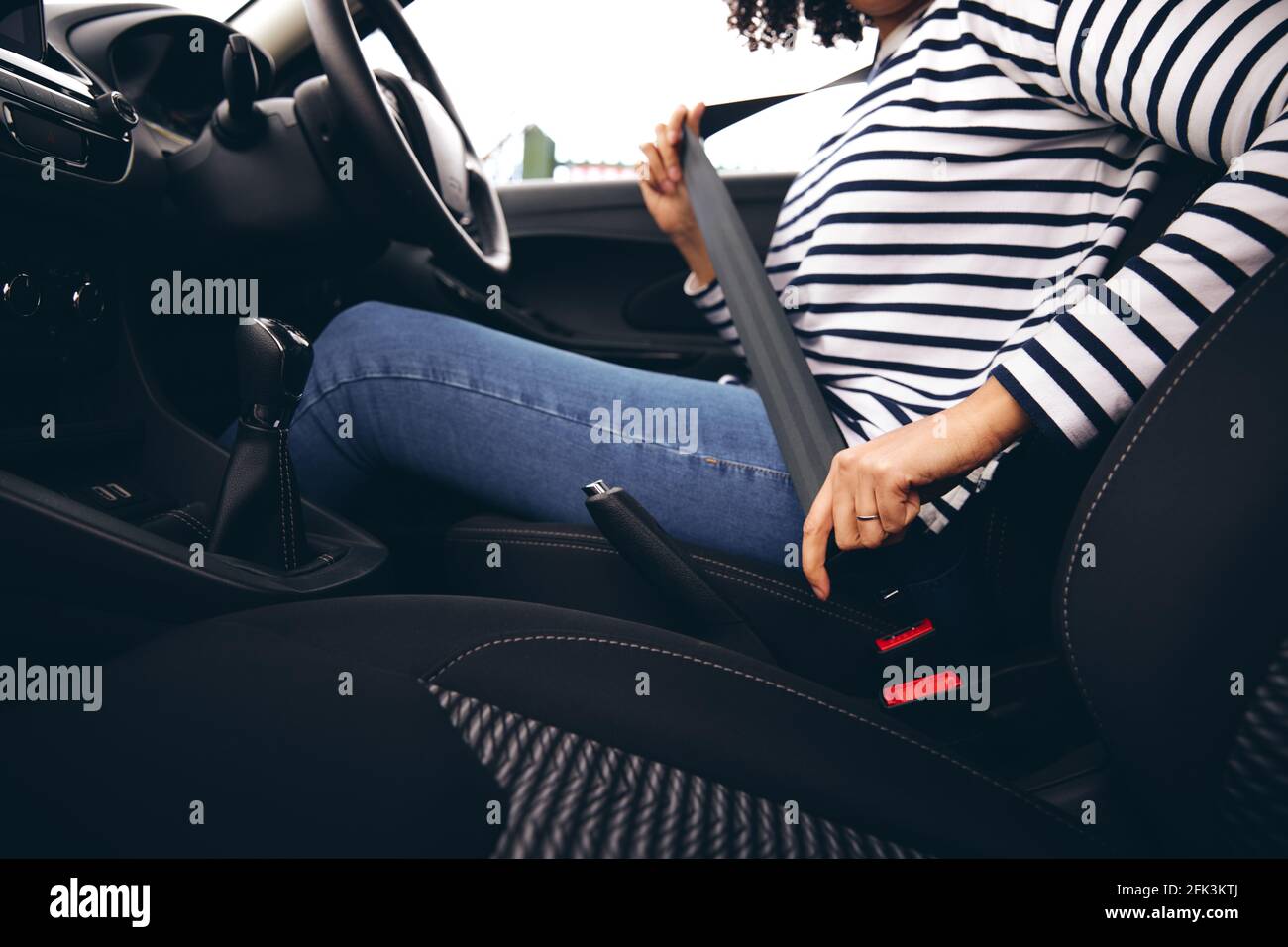 Close up of female driver in car fastening seatbelt at start of journey Stock Photo