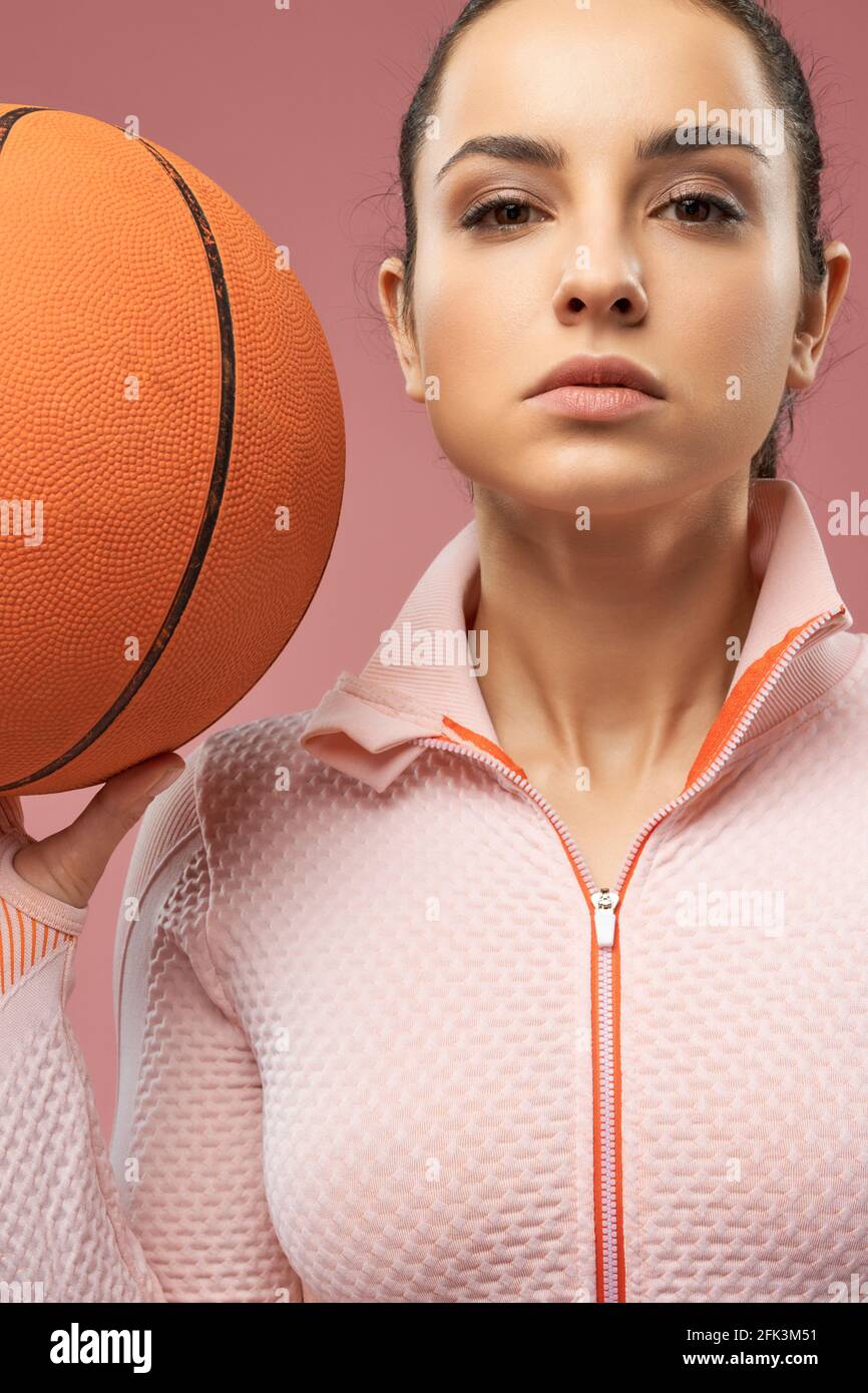 Beautiful young woman holding orange basketball ball Stock Photo