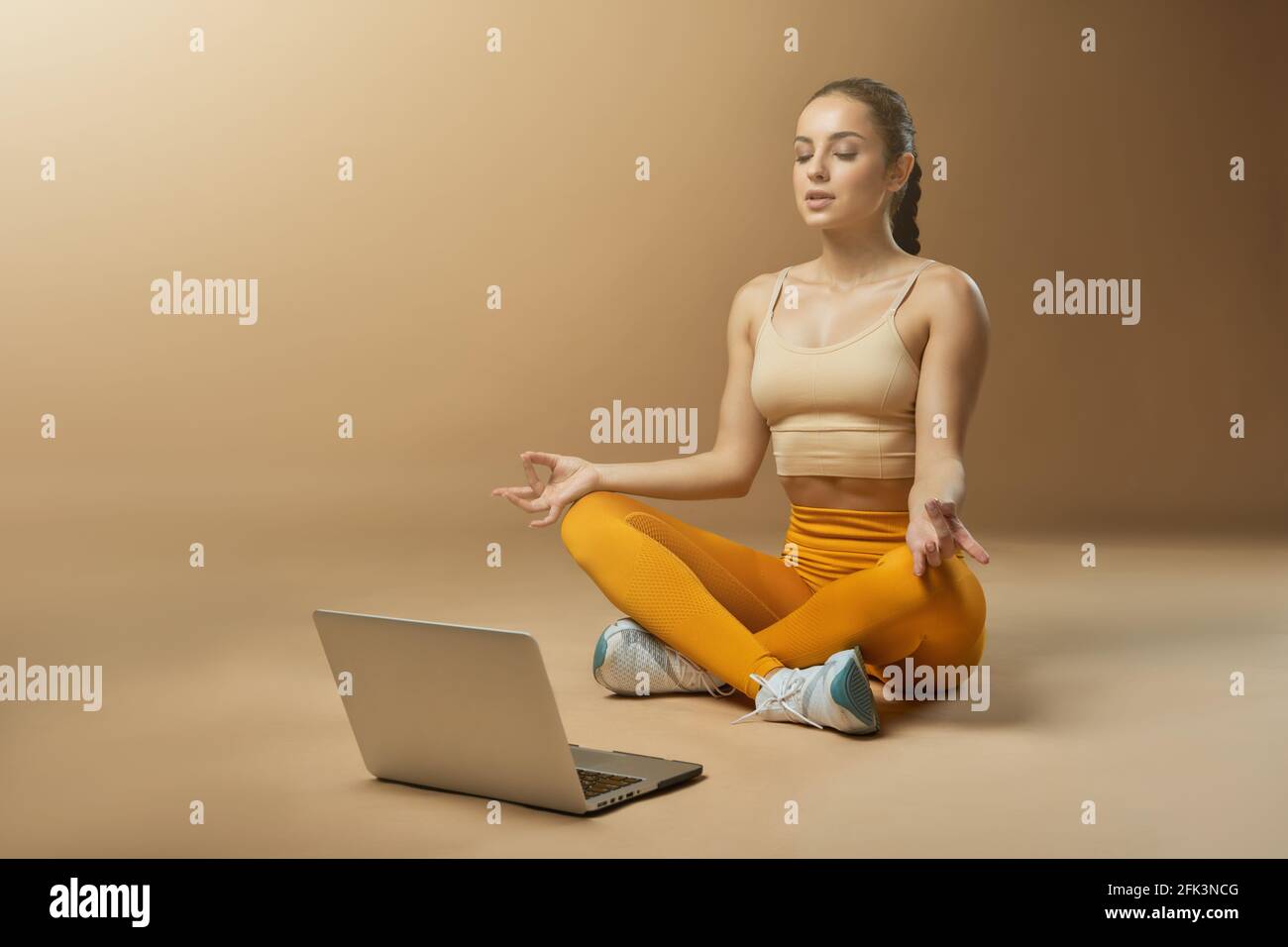 Beautiful young woman using laptop and meditating Stock Photo