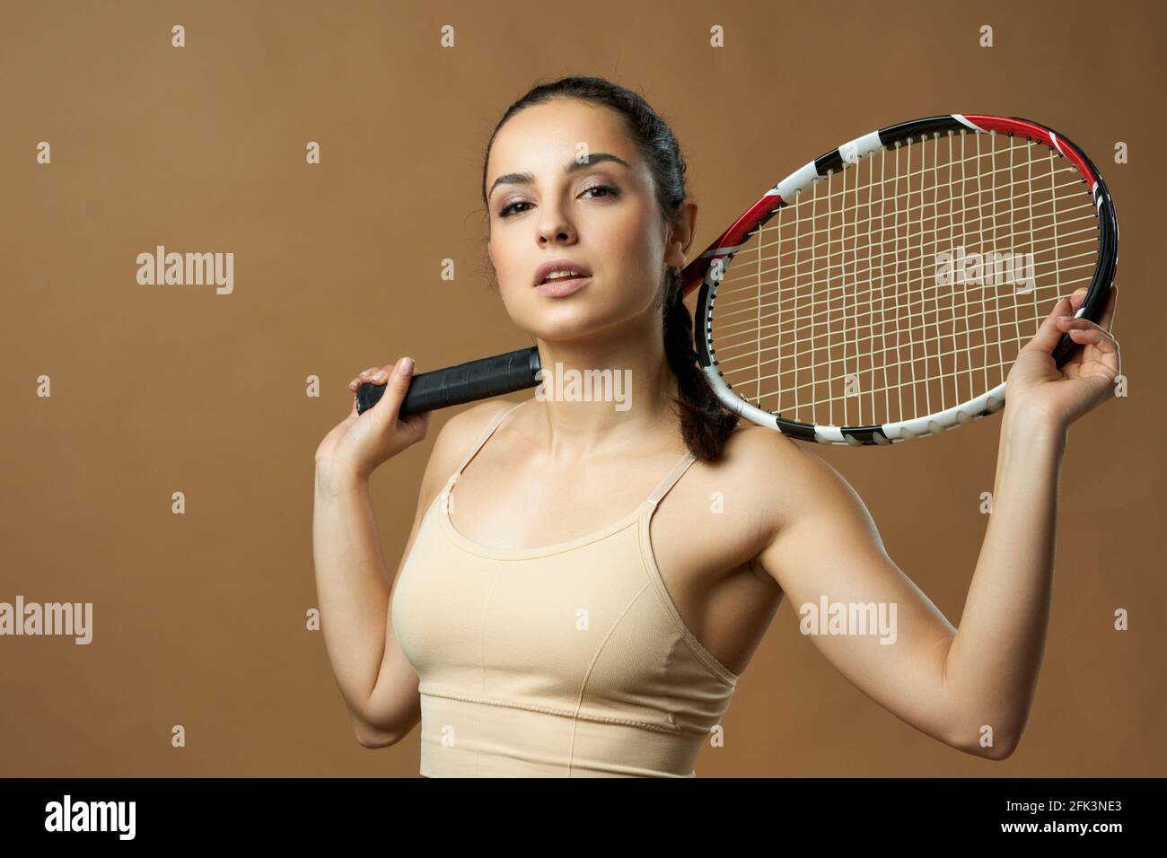 Charming young woman with tennis racket posing in studio Stock Photo