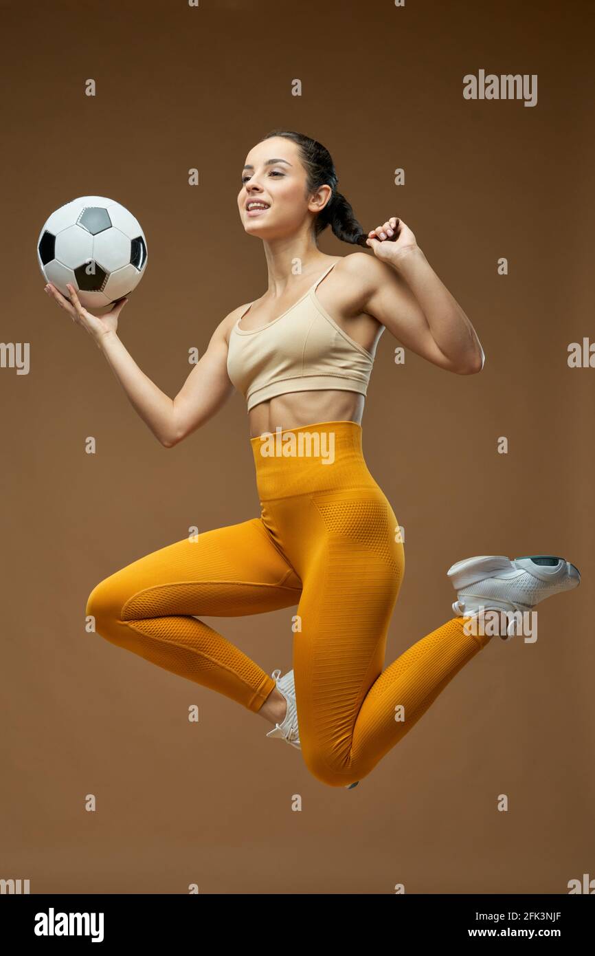 Cheerful young woman with soccer ball jumping on the air Stock Photo