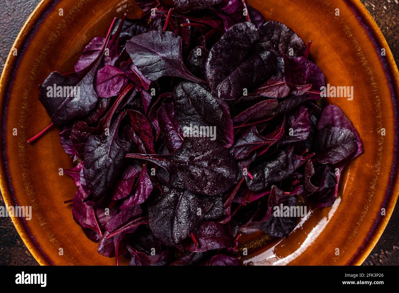 Raw Ruby or red chard salad Leafs on a rustic plate. Dark background. Top view Stock Photo