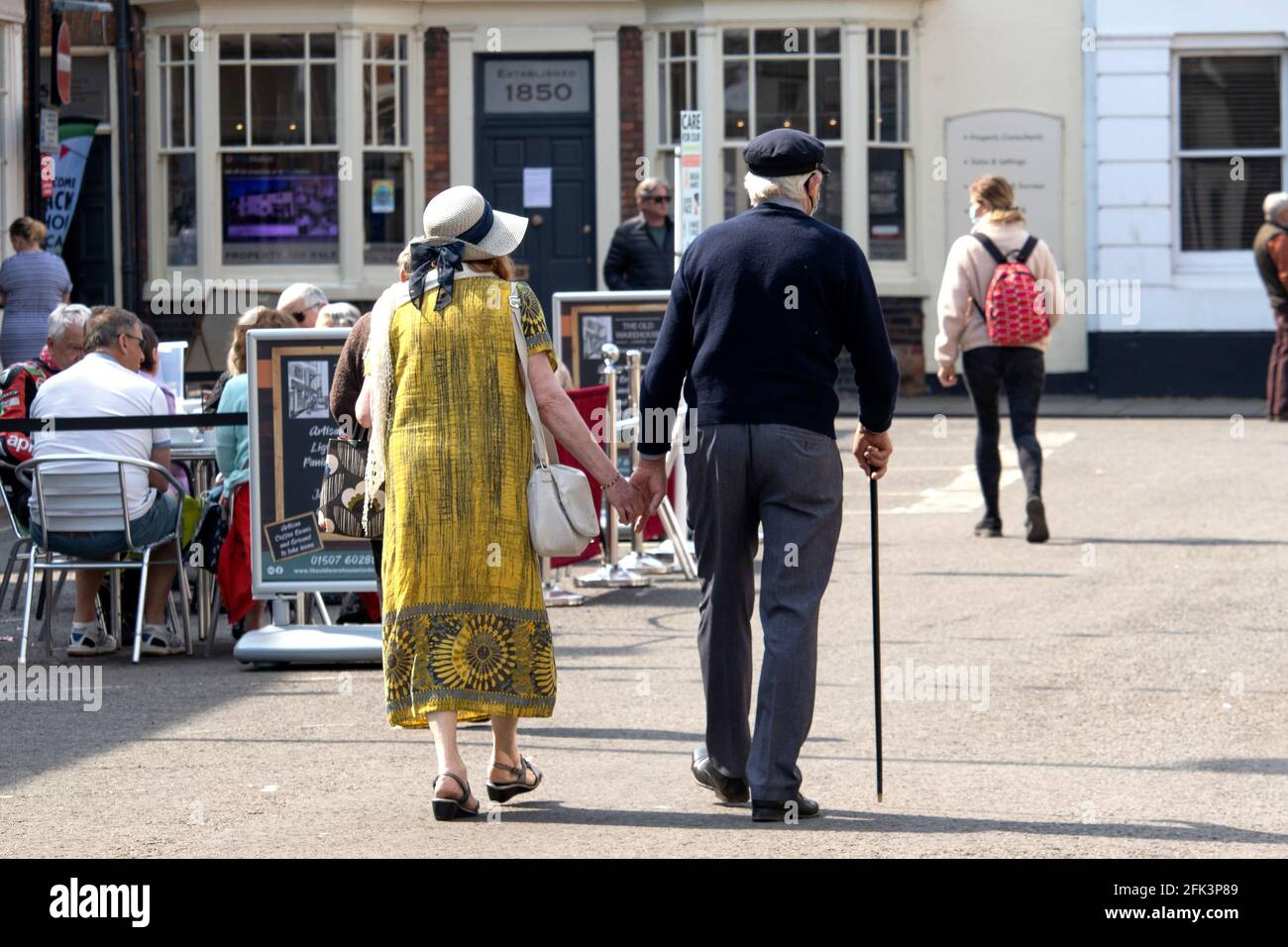 A mature older couple holding hands walking through Louth town centre. Stock Photo