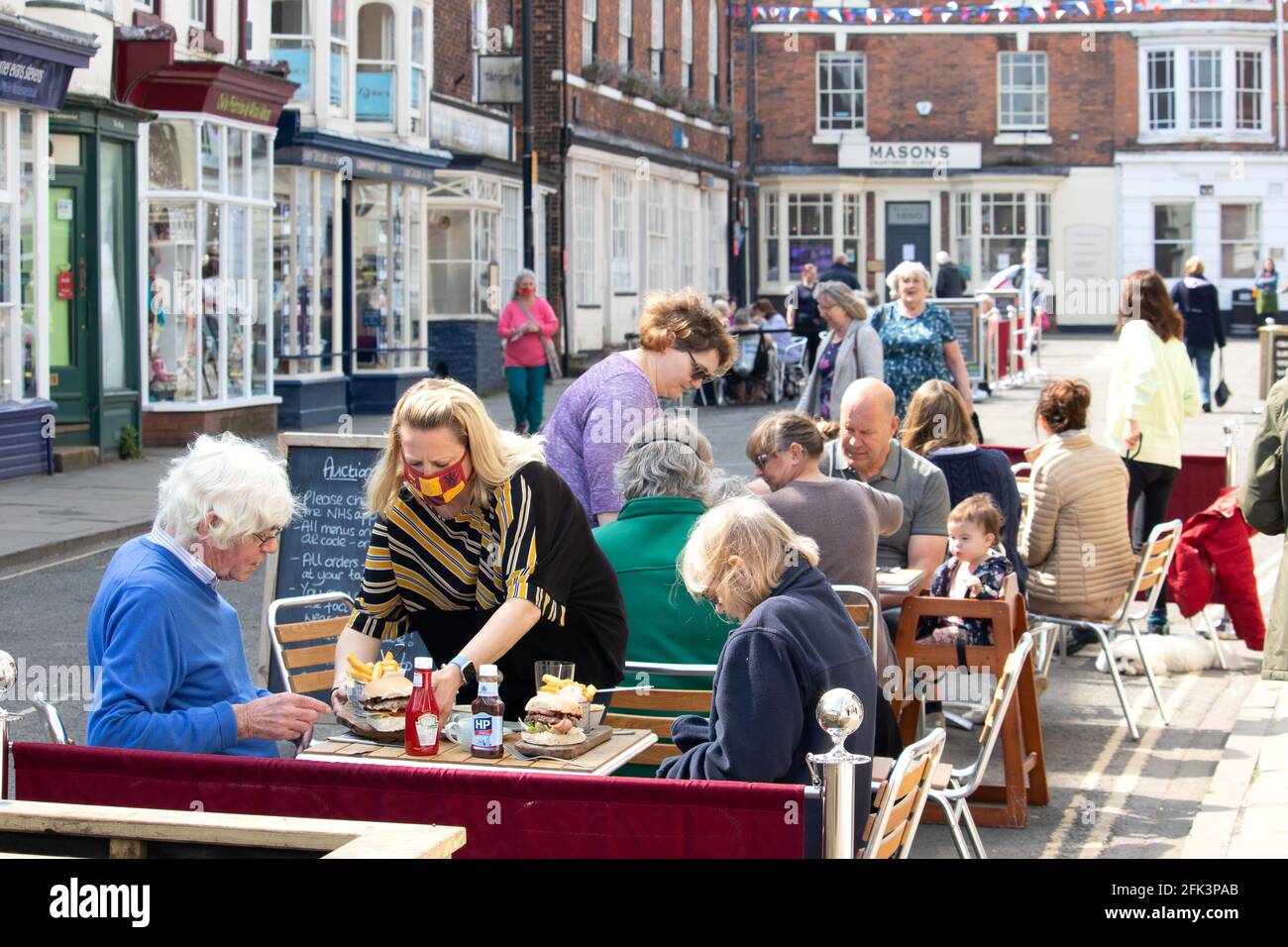 People eating outside in the cormarket area of louth, Lincolnshire during Covid restrictions in April 2021 Stock Photo