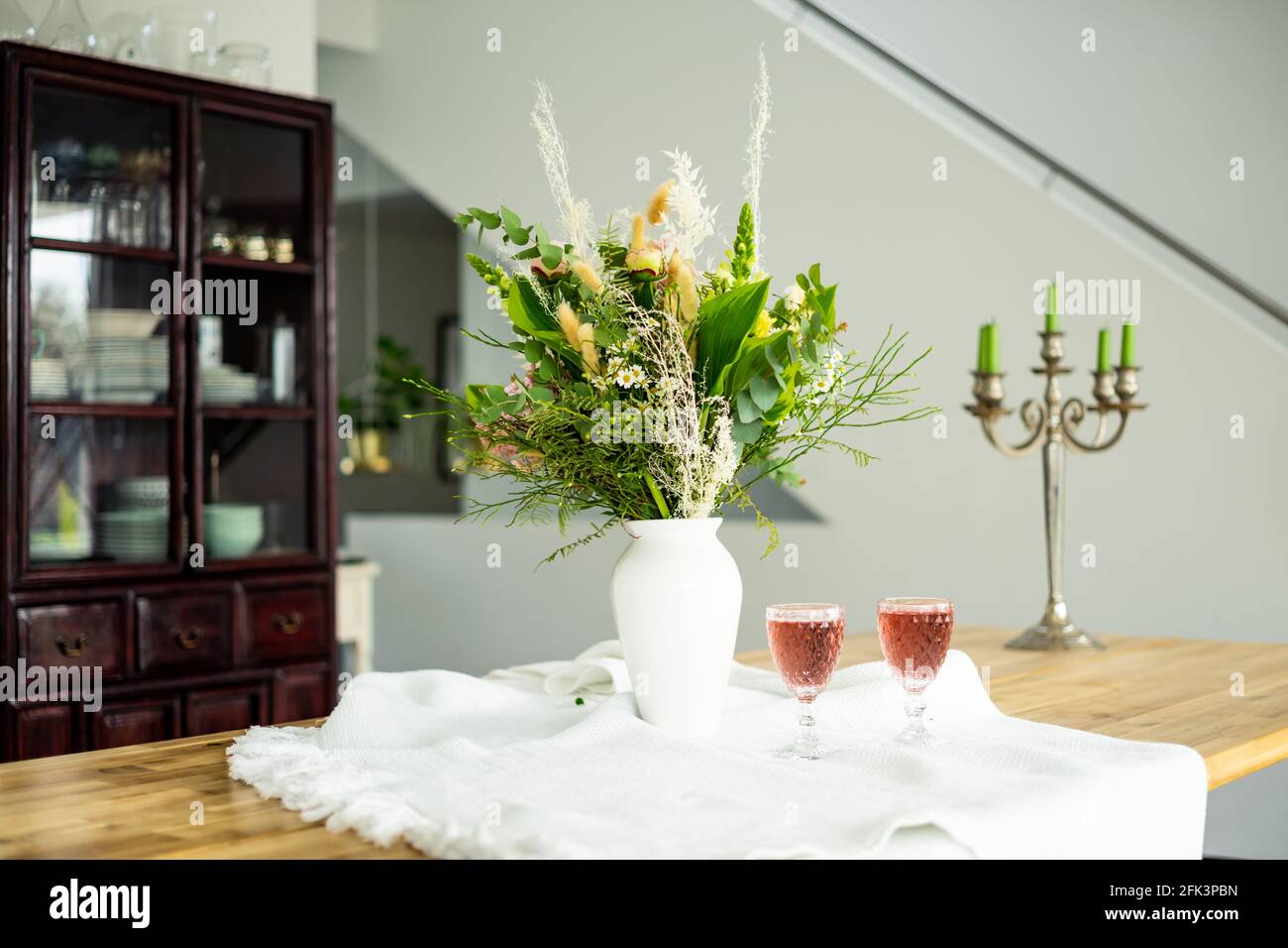 Elegant flower bouquet on a table accompanied by two cocktail goblets in a spacious modern house Stock Photo