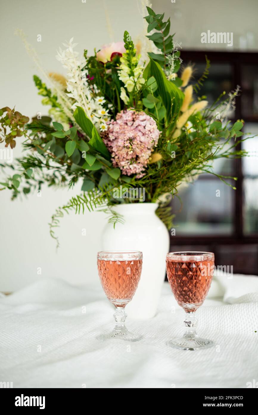 Elegant flower bouquet on a table accompanied by two cocktail goblets in a  spacious modern house Stock Photo - Alamy