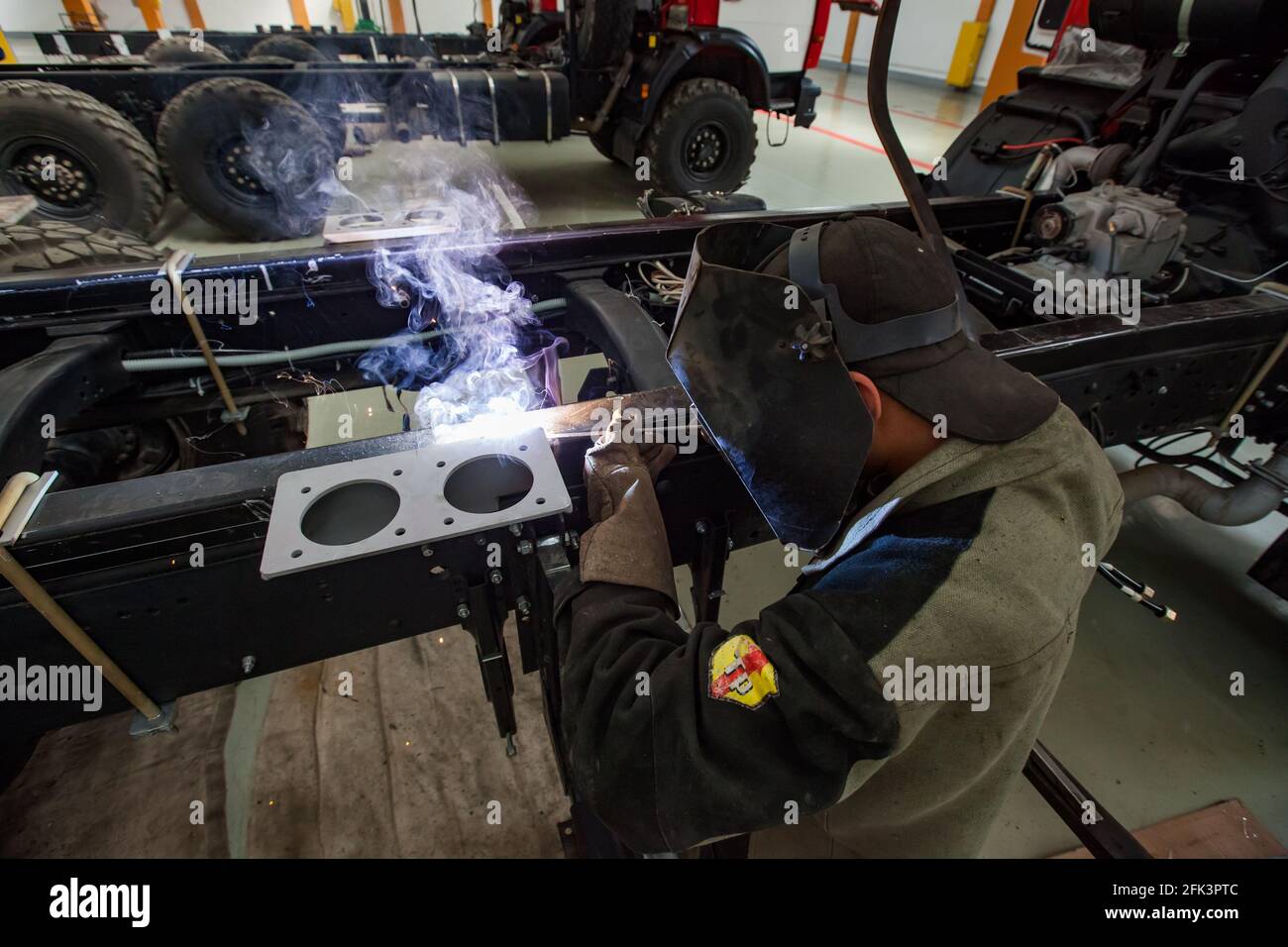 Uralsk, Kazakhstan - May 05,2012: Welder in protective mask and work suit welding metal part of vehicle. Stock Photo