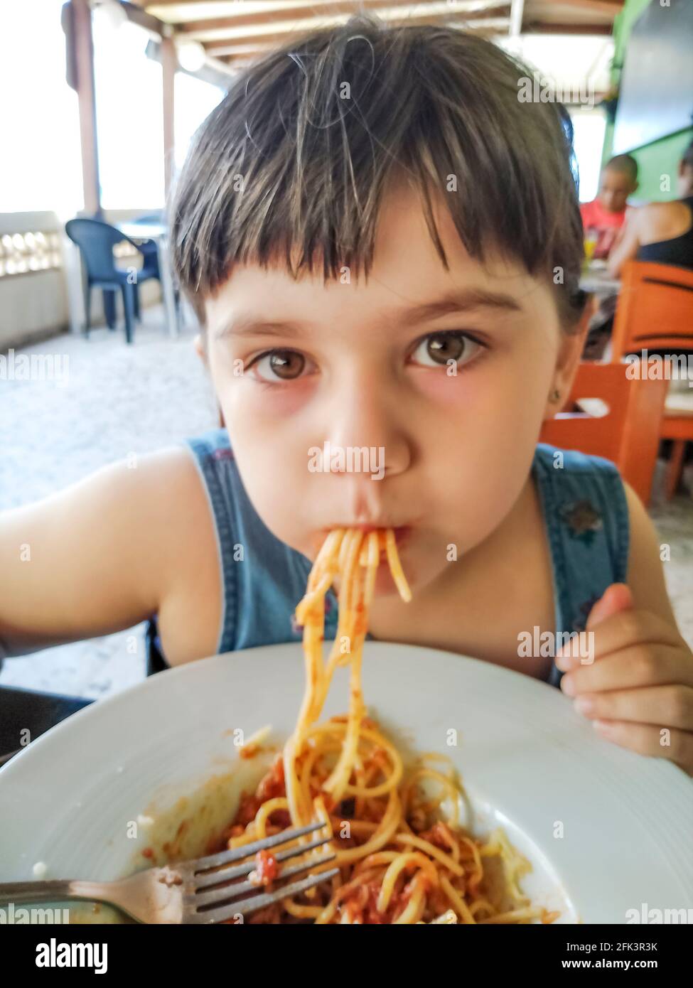 Little girl eating spaghetti in a really untidy manner Stock Photo