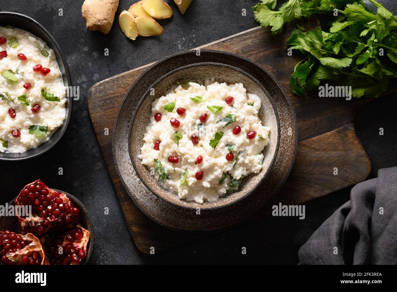 Homemade Curd Rice with pomegranate, cilantro, ginger on a black background. Top view. Traditional Indian South cuisine Stock Photo